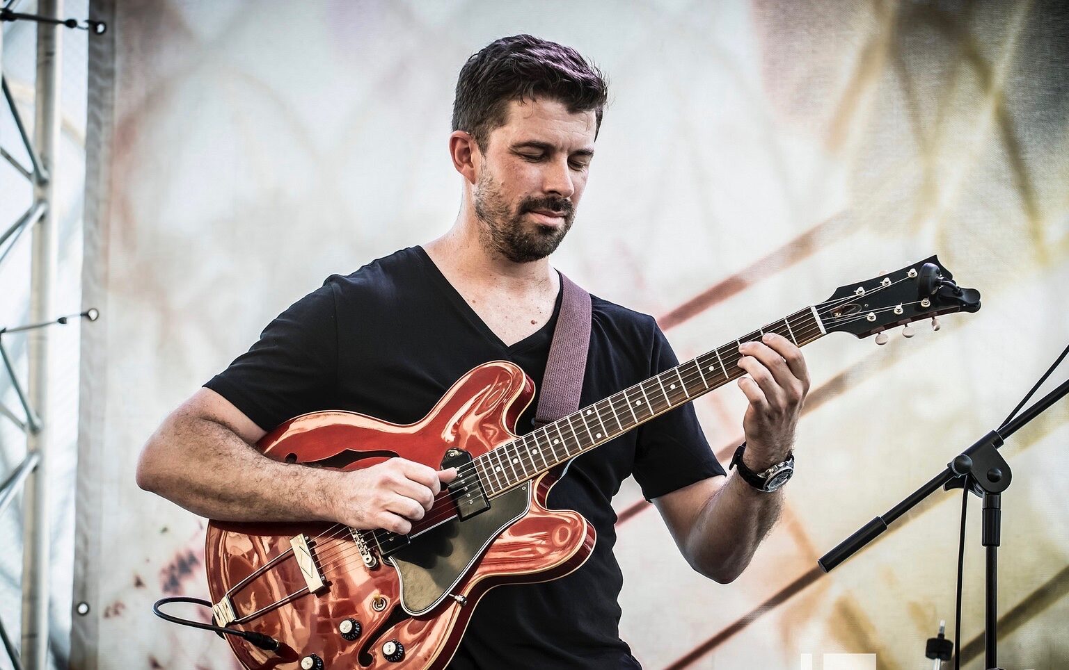 Michael Bester expressively playing an a red Gibson guitar on stage